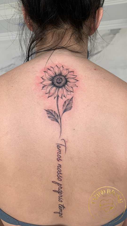Tatuagem escrita com flor nas costas.