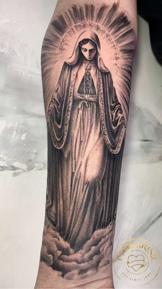 Tatuagem realista de Nossa Senhora no antebraço.