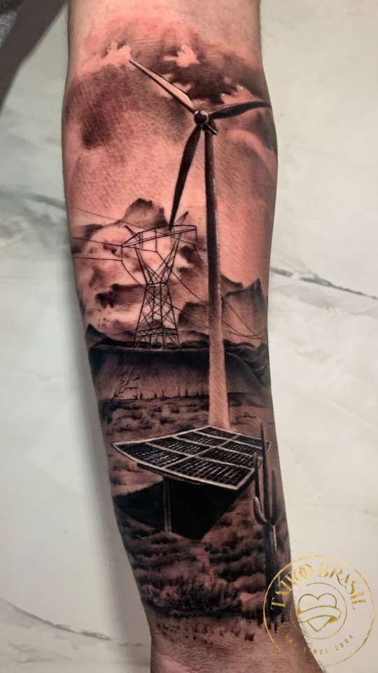 Tatuagem realista de paisagem com turbina eólica e placa solar no braço.